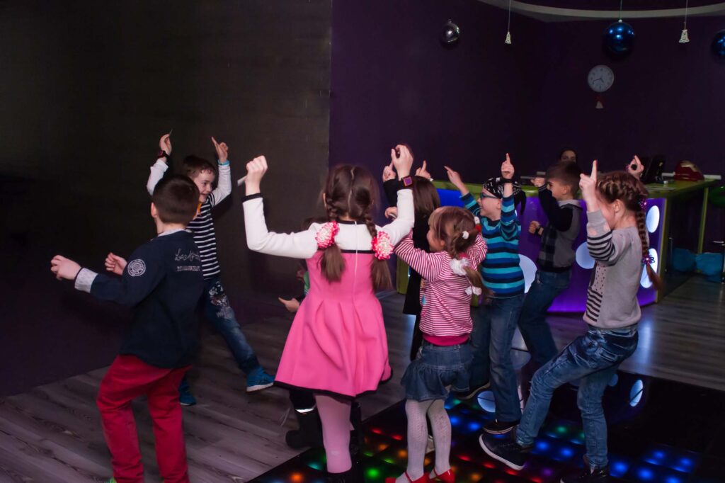 Children dancing at a party disco on a light-up dance floor