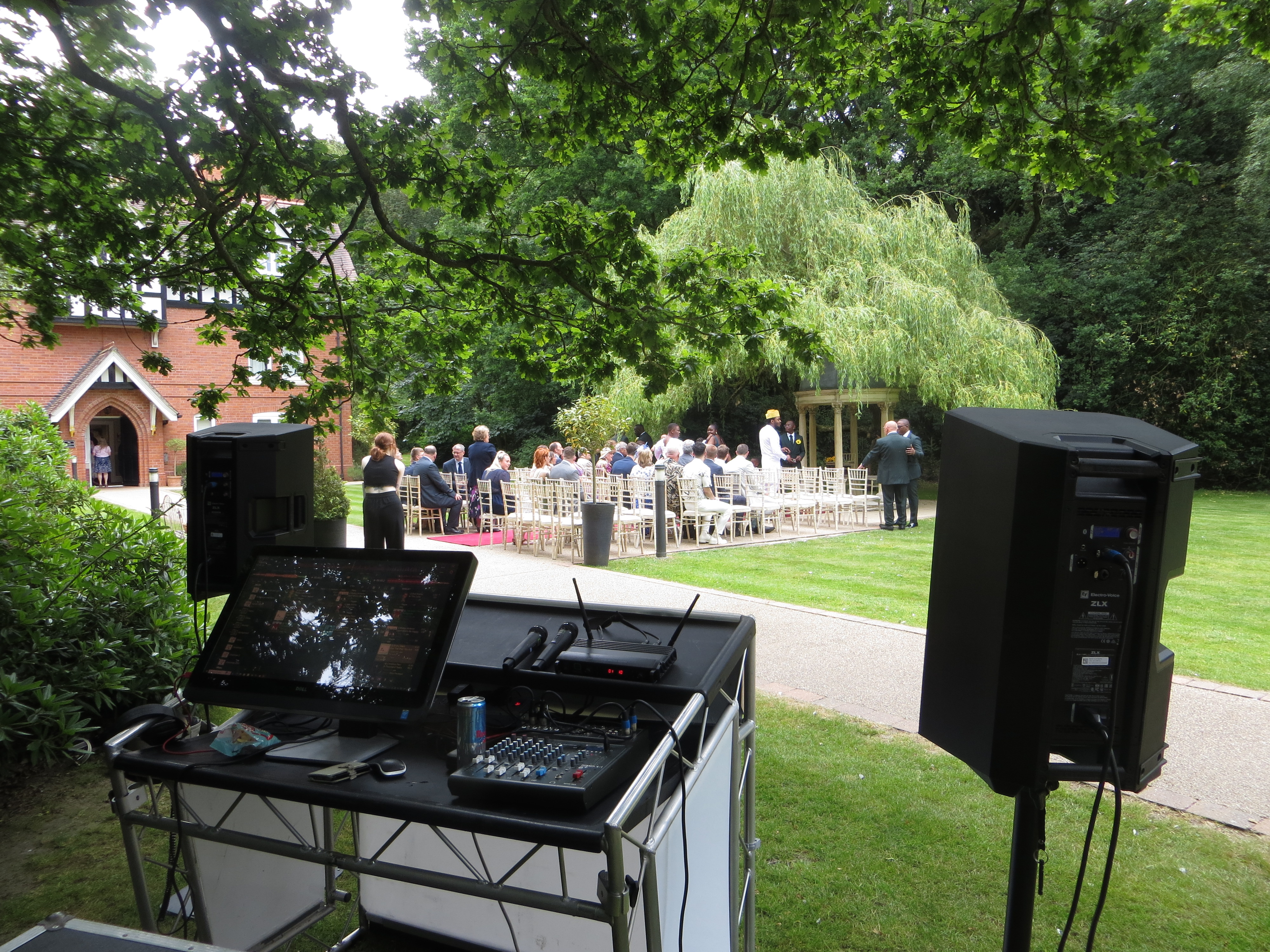 Guests seated for a garden wedding ceremony in Norfolk, with music played live by Tim