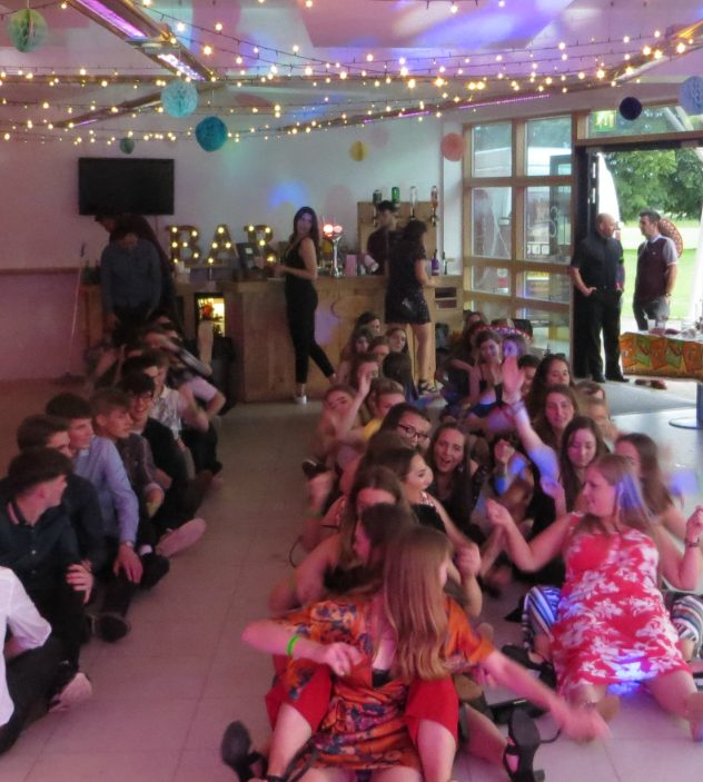 Teenagers dancing together at a prom party under fairy lights